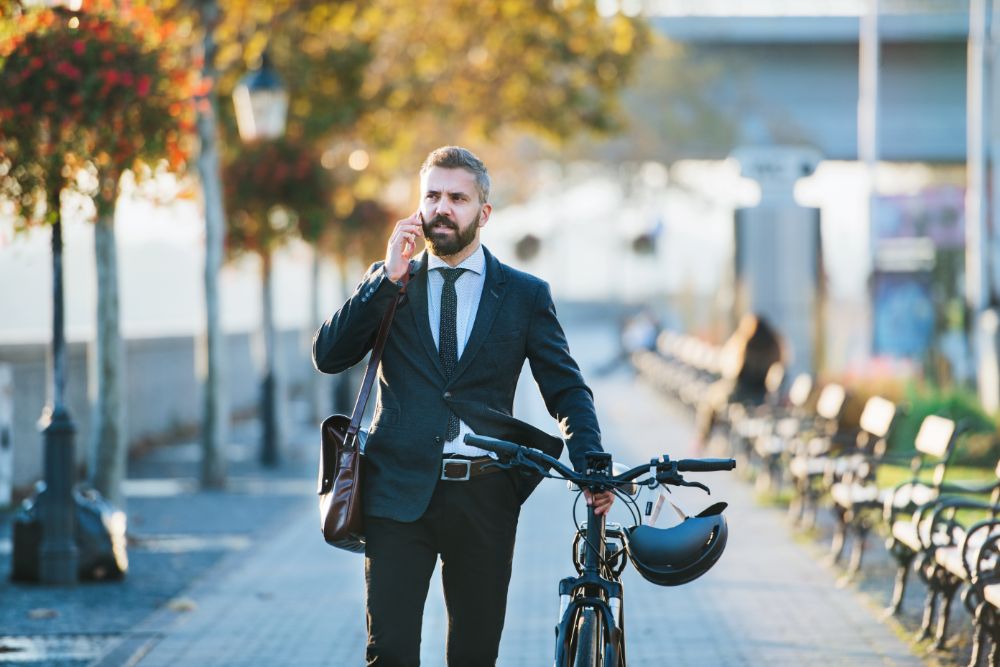 Business man calling next to bicycle